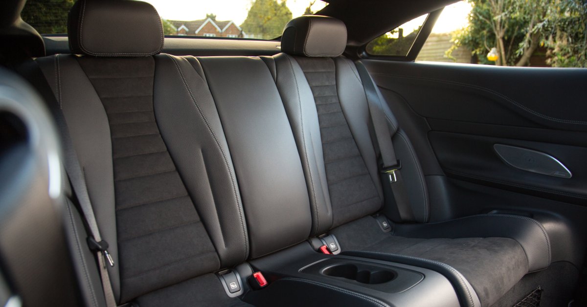 Empty, spacious seats in the back of a vehicle. The black leather and fabric look brand new and very clean.
